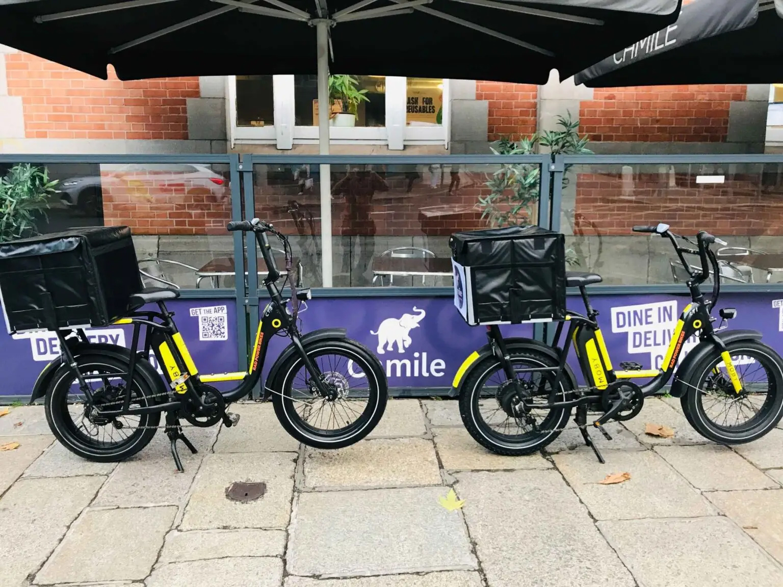 Two MOBY e-bikes with delivery top boxes parked outside a Camile Thai restaurant